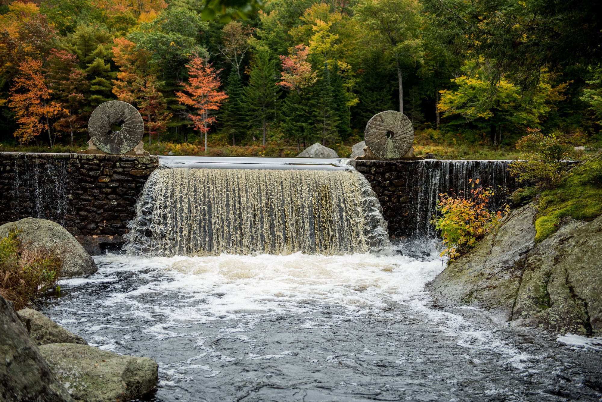 The waterfall pouring over the dam between two millstones