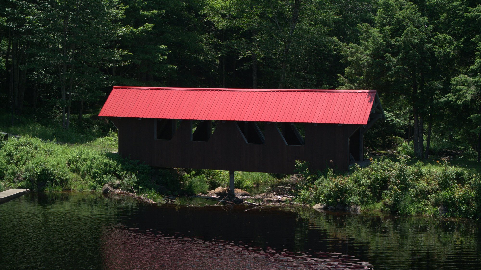 The covered bridge and its red roof at the head of the pond