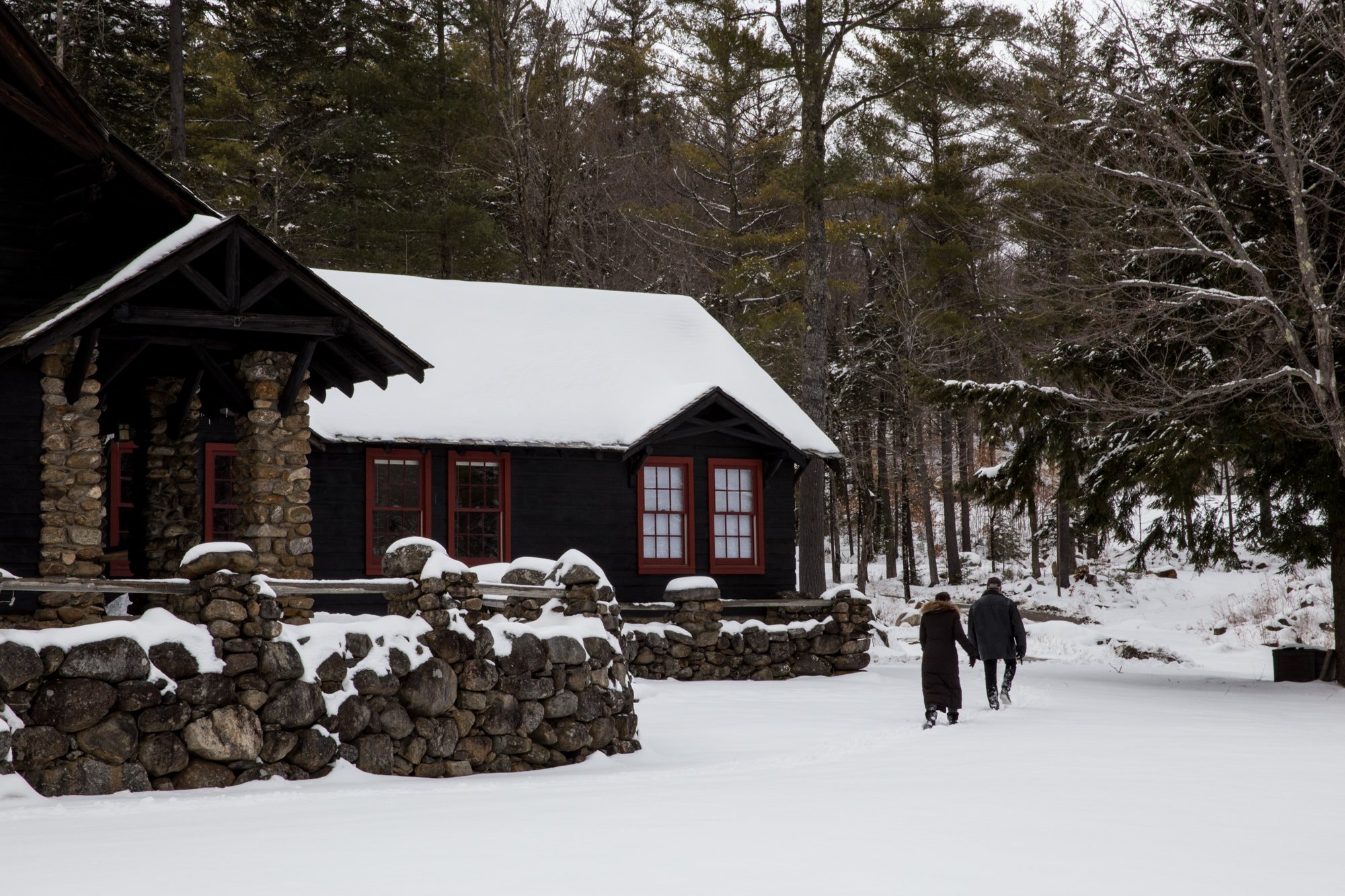Two figures walking toward a snowy cabin